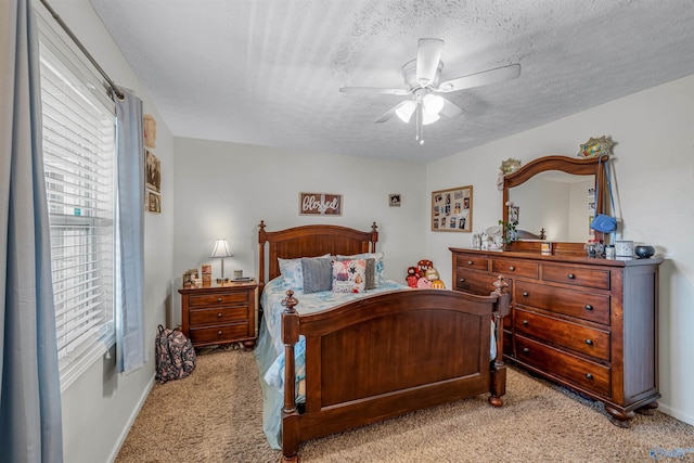 bedroom featuring light colored carpet, a ceiling fan, and a textured ceiling