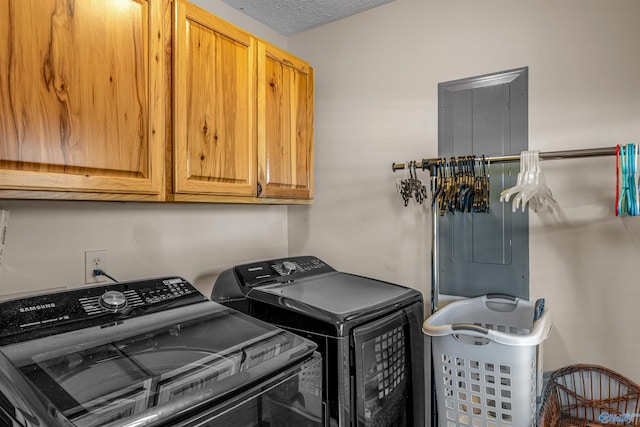 washroom featuring washing machine and clothes dryer, cabinet space, and a textured ceiling