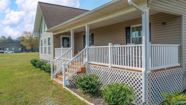 view of front facade with a front yard, a shingled roof, and a porch