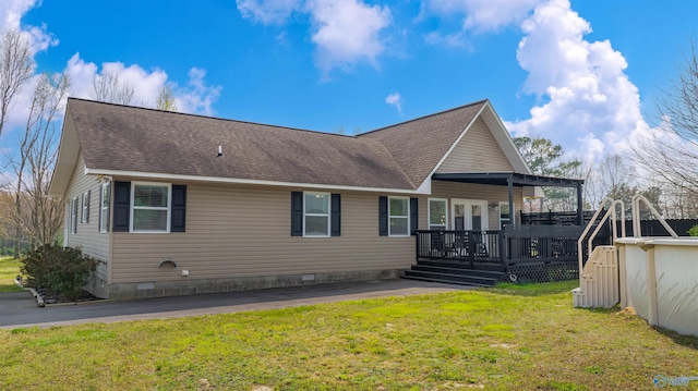 view of front of house with a front lawn, crawl space, a deck, and roof with shingles
