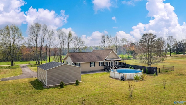 back of property with a lawn, an outbuilding, fence, and a fenced in pool