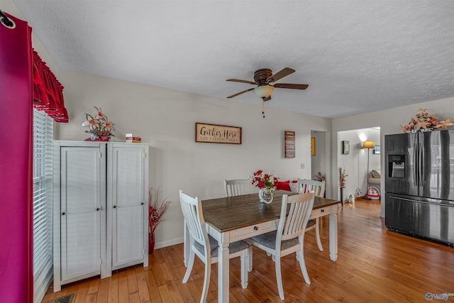 dining space with a textured ceiling, ceiling fan, visible vents, and light wood-type flooring
