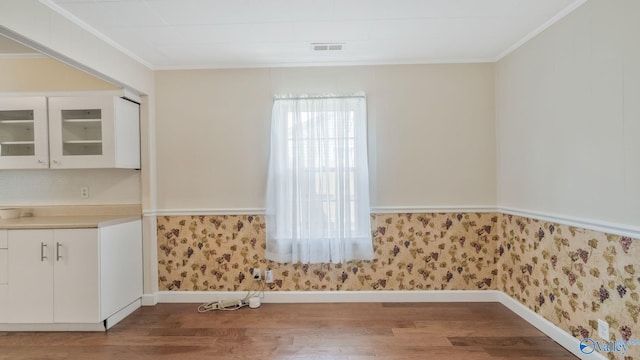 701 10th St NW, Huntsville, AL 35805 - unfurnished dining area with baseboards, ornamental molding, wallpapered walls, and wood finished floors
