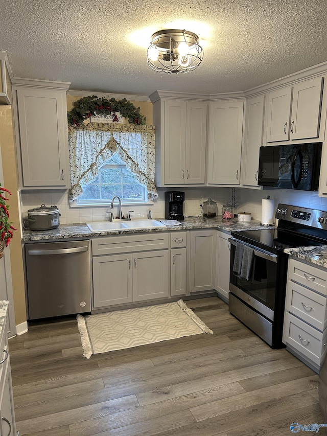 kitchen featuring hardwood / wood-style flooring, white cabinetry, appliances with stainless steel finishes, and sink