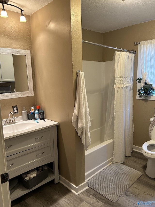 full bathroom featuring hardwood / wood-style flooring, vanity, a textured ceiling, toilet, and shower / bath combo with shower curtain