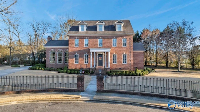 colonial house with brick siding and a fenced front yard