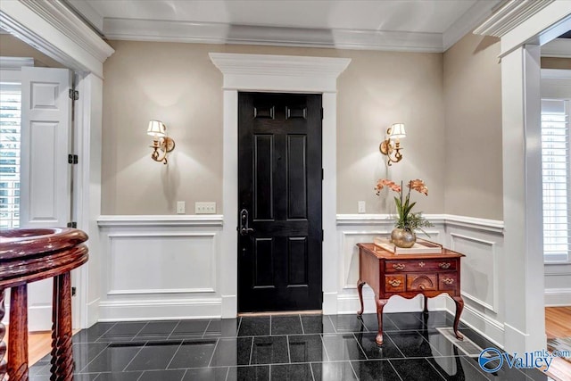 foyer with a wainscoted wall, granite finish floor, plenty of natural light, ornamental molding, and a decorative wall