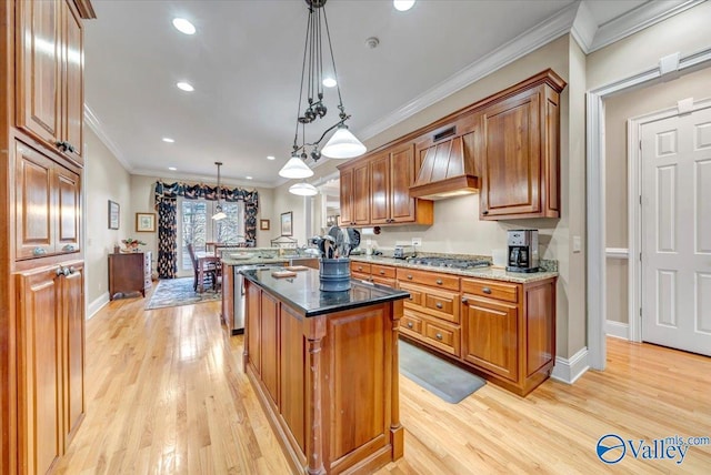 kitchen with light wood-style flooring, brown cabinets, crown molding, and premium range hood