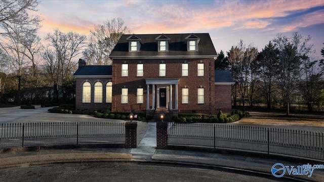 colonial home with brick siding and a fenced front yard