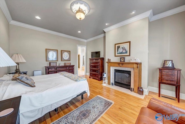 bedroom with a fireplace, light wood-type flooring, baseboards, and ornamental molding