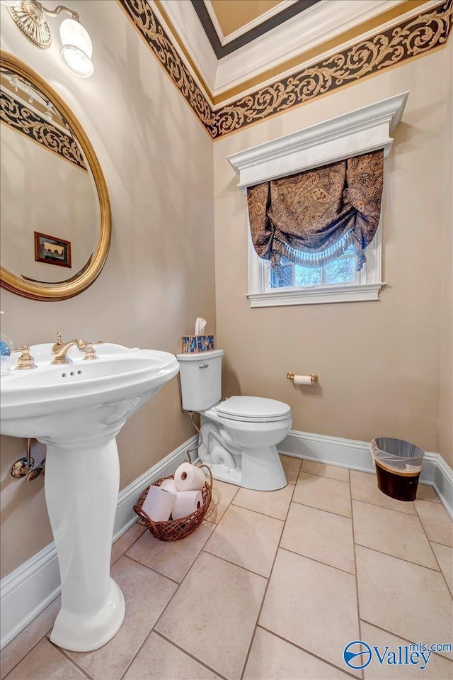 bathroom with tile patterned flooring, toilet, baseboards, and a sink