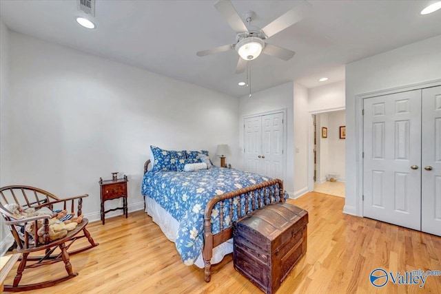 bedroom with light wood-type flooring, visible vents, baseboards, and two closets