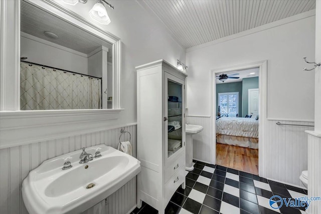 full bathroom featuring a sink, wainscoting, tile patterned floors, toilet, and connected bathroom