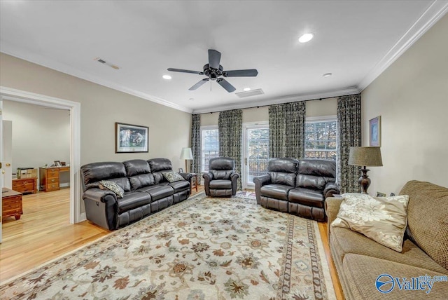 living area with visible vents, crown molding, a ceiling fan, and wood finished floors