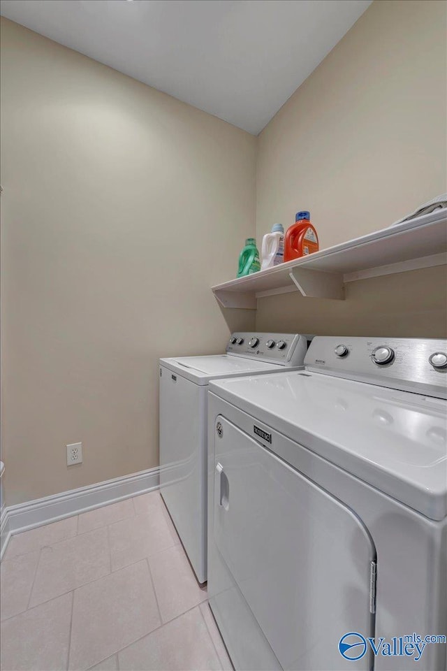 clothes washing area featuring washer and clothes dryer, laundry area, baseboards, and light tile patterned floors