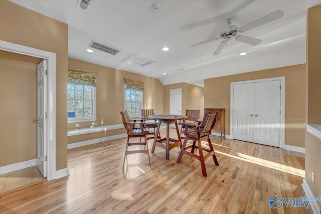 dining area with visible vents, baseboards, attic access, lofted ceiling, and light wood-style floors