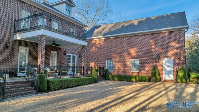 view of front of house featuring a ceiling fan, brick siding, and a balcony