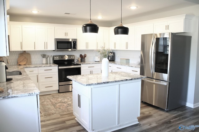 kitchen with hanging light fixtures, stainless steel appliances, decorative backsplash, white cabinetry, and wood-type flooring