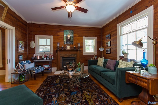 living room with ornamental molding, hardwood / wood-style flooring, wooden walls, and ceiling fan