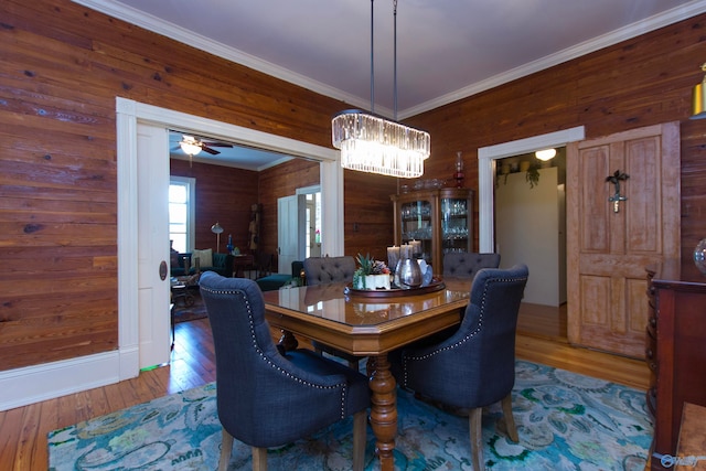 dining room with ceiling fan, hardwood / wood-style flooring, crown molding, and wood walls