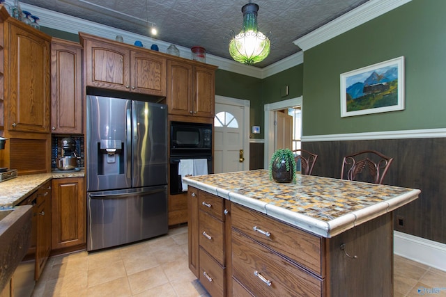 kitchen featuring a kitchen island, black appliances, crown molding, light tile patterned floors, and a textured ceiling