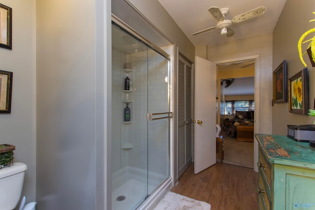 bathroom featuring ceiling fan, wood-type flooring, toilet, and walk in shower