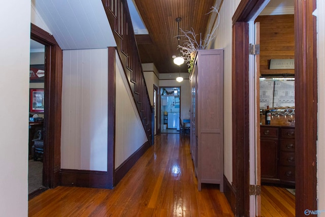 corridor with wooden walls, vaulted ceiling, wood ceiling, and dark hardwood / wood-style floors