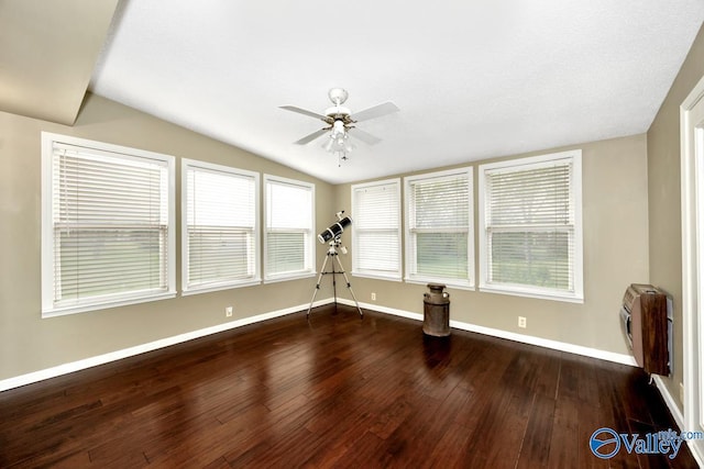 empty room featuring baseboards, vaulted ceiling, a ceiling fan, heating unit, and wood-type flooring