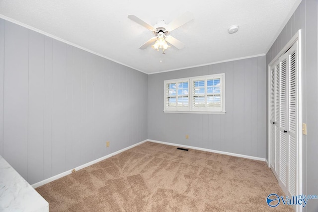 unfurnished bedroom with crown molding, a closet, carpet flooring, and visible vents