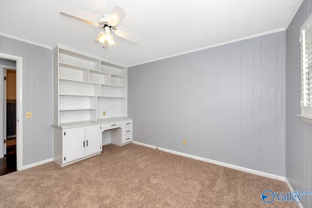 unfurnished bedroom featuring ornamental molding, a ceiling fan, a textured ceiling, built in study area, and light carpet