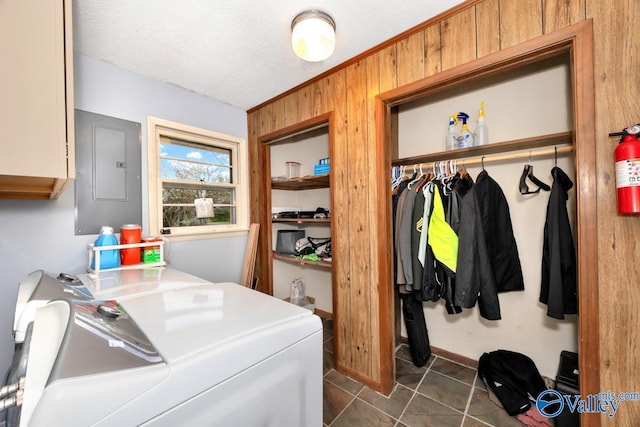 laundry area with separate washer and dryer, electric panel, a textured ceiling, cabinet space, and wood walls