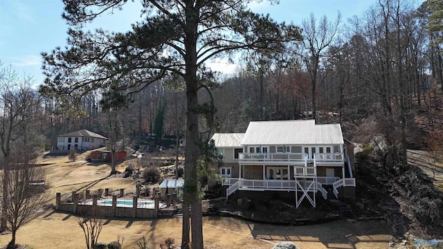 back of house featuring a balcony, covered porch, and a swimming pool