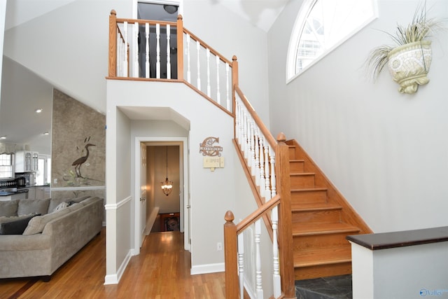 staircase featuring hardwood / wood-style flooring and a towering ceiling