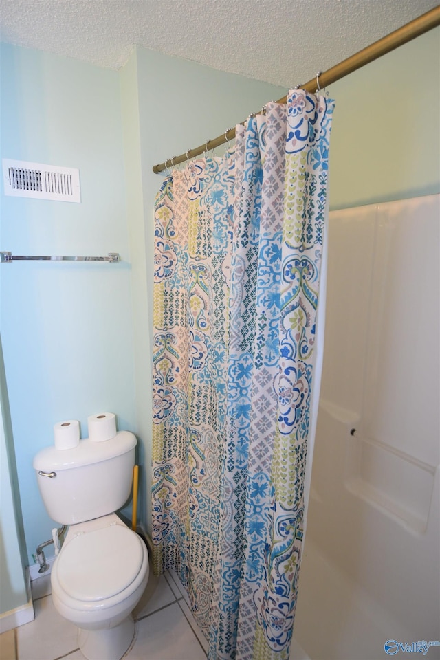 bathroom with tile patterned floors, toilet, a textured ceiling, and walk in shower