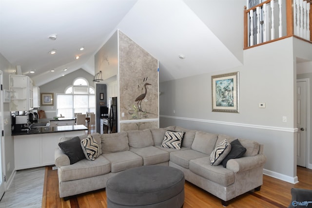 living room featuring high vaulted ceiling, sink, and light wood-type flooring