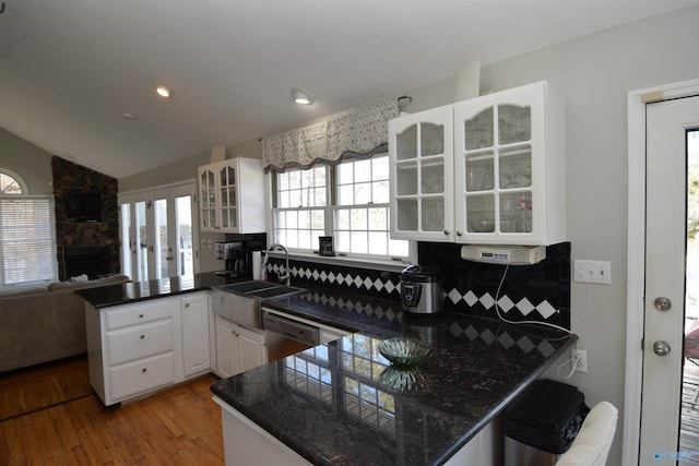 kitchen with sink, hardwood / wood-style floors, white cabinets, stainless steel dishwasher, and kitchen peninsula