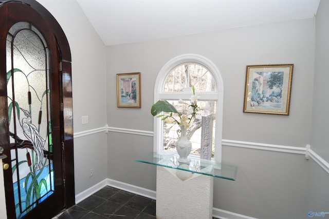 entrance foyer with dark tile patterned floors and lofted ceiling