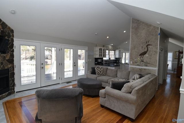 living room with hardwood / wood-style floors, a fireplace, high vaulted ceiling, and french doors