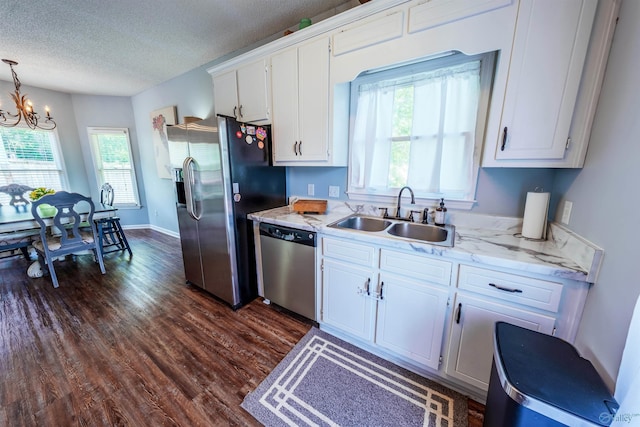 kitchen with a chandelier, white cabinets, a sink, dark wood finished floors, and appliances with stainless steel finishes