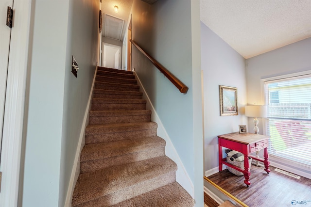 stairs with attic access, baseboards, wood finished floors, lofted ceiling, and visible vents