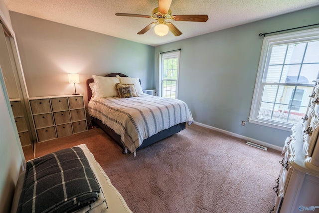 bedroom featuring carpet flooring, a textured ceiling, visible vents, and baseboards