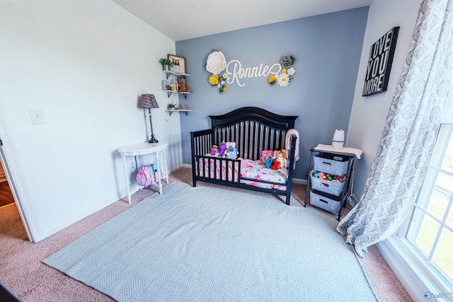 bedroom featuring baseboards, carpet flooring, and a nursery area