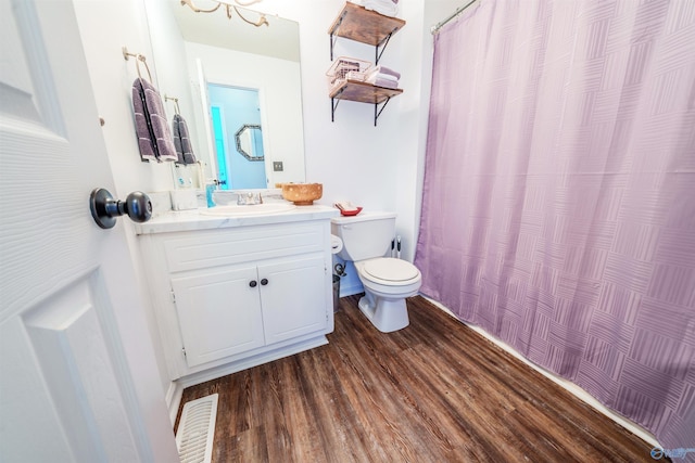 full bath with a shower with curtain, visible vents, wood finished floors, vanity, and toilet