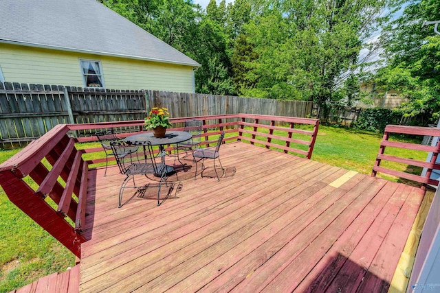 wooden deck featuring a fenced backyard, outdoor dining area, and a lawn