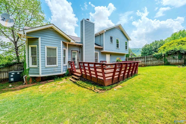 back of house featuring a fenced backyard, a yard, a chimney, and a deck