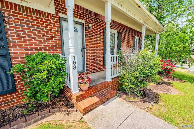 doorway to property featuring a porch and brick siding