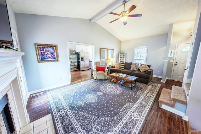 living area with wood finished floors, a fireplace, baseboards, ceiling fan, and lofted ceiling with beams