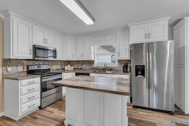 kitchen with white cabinets, appliances with stainless steel finishes, light hardwood / wood-style flooring, and sink