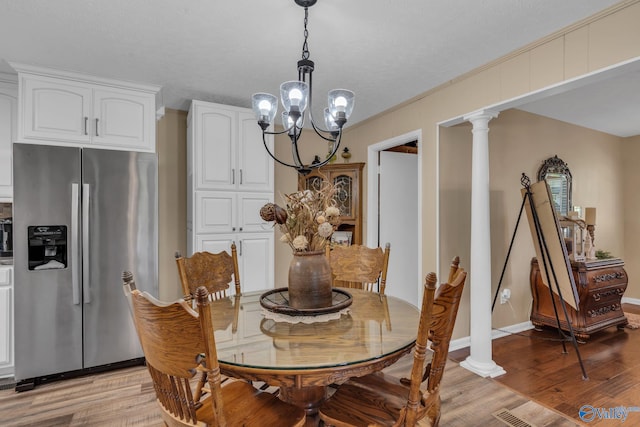 dining area with a notable chandelier, light hardwood / wood-style floors, ornate columns, and crown molding