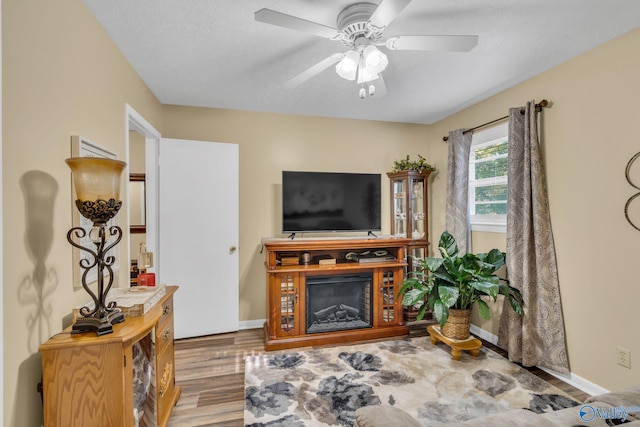 living room featuring ceiling fan, wood-type flooring, and a textured ceiling